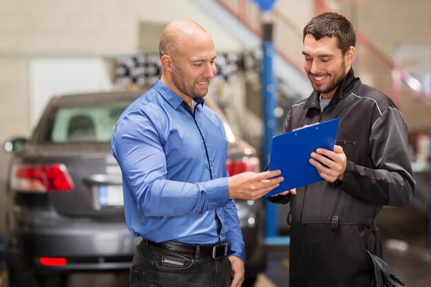 Foto mantenimiento de servicio de reparación de automóviles y concepto de personas mecánico con clipboard y cliente o propietario del automóvil en el taller