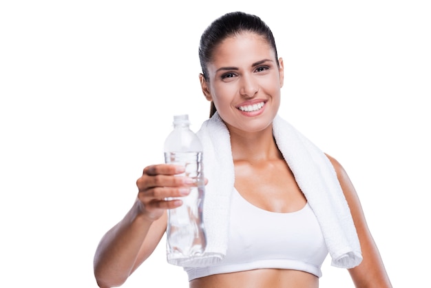 ¡Mantente fresco e hidratado! Hermosa mujer joven en sujetador blanco y bragas sosteniendo una botella con agua y sonriendo mientras está de pie aislado en blanco