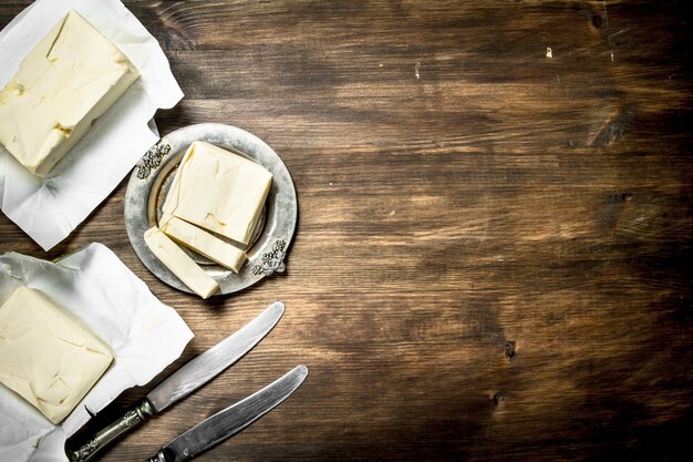 Mantequilla con cuchillo sobre mesa de madera.