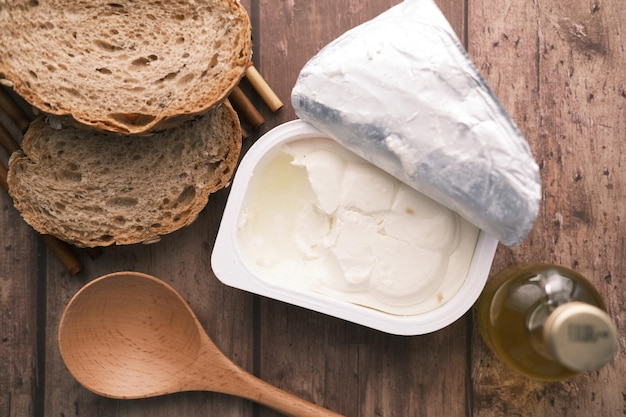 Mantequilla fresca en un recipiente con pan sobre fondo blanco.