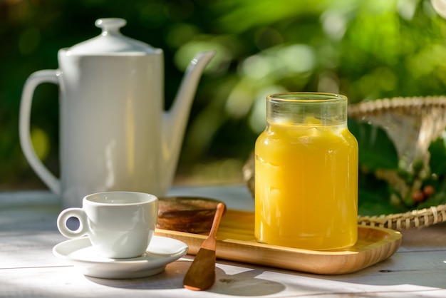 Mantequilla de ghee en frasco de vidrio sobre la mesa del desayuno con taza y tetera blanca