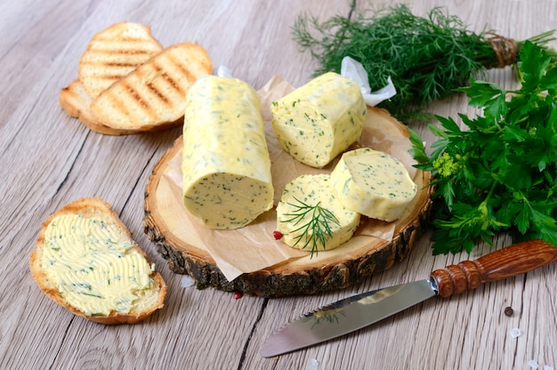 Mantequilla con una hierba para sándwiches y bistec. Porción de mantequilla de hierbas en rodajas sobre una tabla de madera. Comida italiana casera.