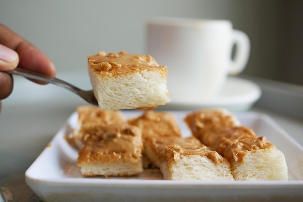 Mantequilla de maní untada en pan y taza de té en la mesa