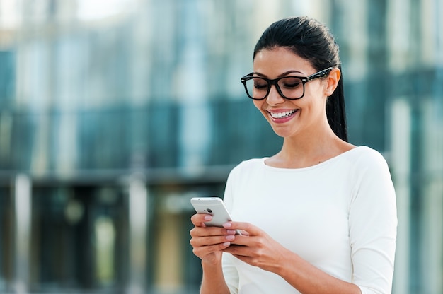 Manter contato com os colegas. Jovem empresária feliz segurando um telefone celular e sorrindo