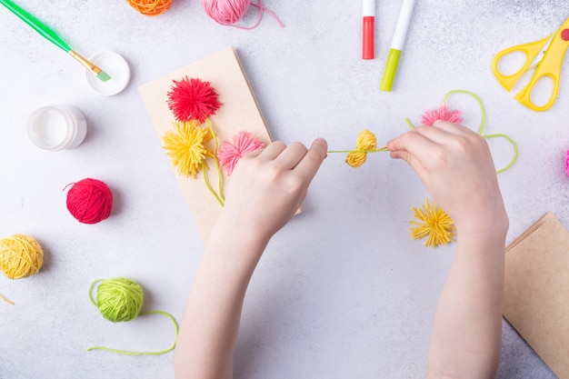 Manualidades de papel para el día de la madre marzo o cumpleaños niño pequeño haciendo un ramo de flores de papel de colores y bolas de tejer de colores para mamá idea de regalo simple vista espacio de copia superior foto de alta calidad