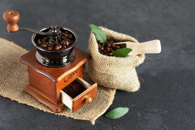 Manuelle WeinleseKaffeemühle und Kaffeebohnen in einem Leinensack auf einem Holztisch.