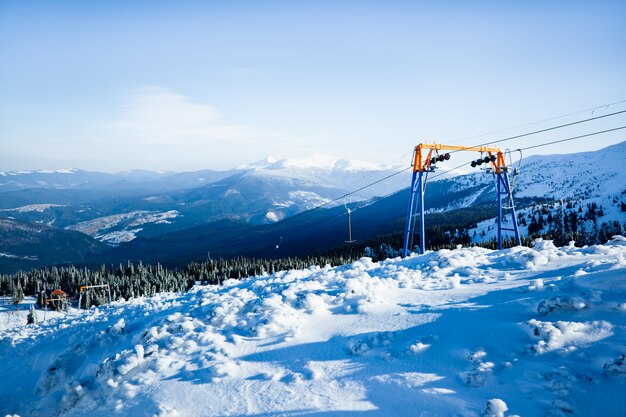 Manueller Skilift und einige Skifahrer mit Bergen und Tal im Hintergrund