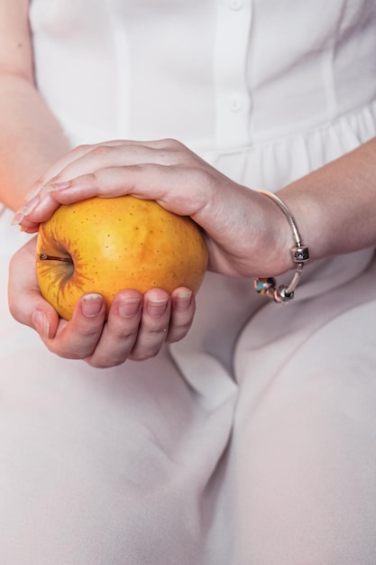 Manzana amarilla madura en tiernas manos femeninas