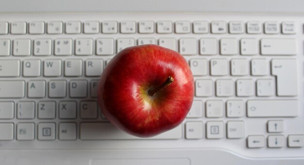 La manzana del concepto del conocimiento la manzana madura perfecta en el teclado blanco desfocalizado de la computadora portátil