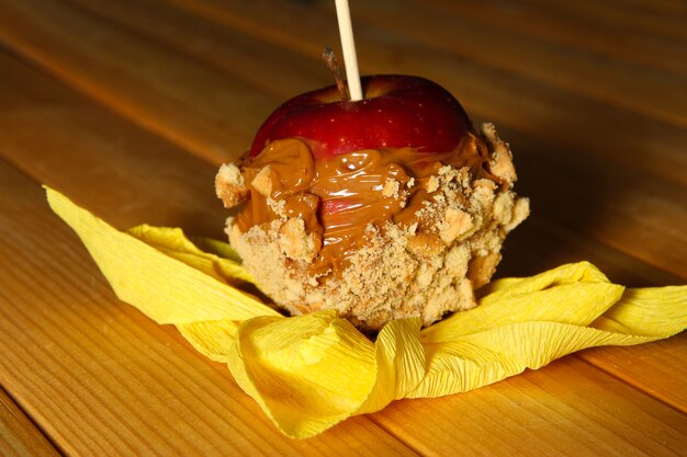 Manzana confitada en palo sobre mesa de madera