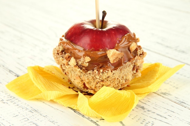 Manzana confitada en palo sobre mesa de madera