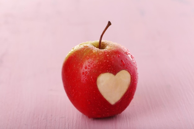 Manzana con corazón en mesa de madera