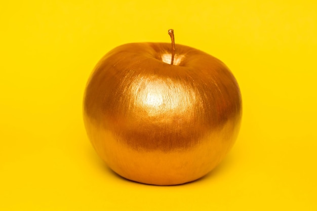 Manzana dorada sobre fondo amarillo Concepto creativo con fruta