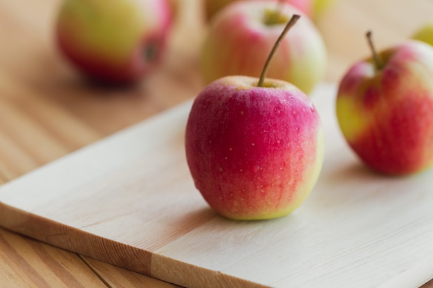 La manzana fresca de Fuji en tabla de cortar puso la tabla de madera para el fondo o el papel pintado.