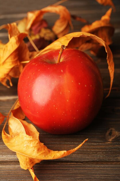 Manzana con hojas secas en un primer plano de mesa de madera