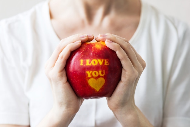 Una manzana con la inscripción "Te amo" en manos de una persona. Concepto de San Valentín