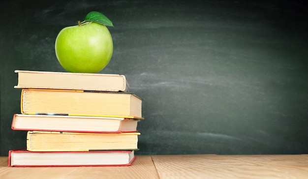 Una manzana en los libros en el fondo de la junta escolar.