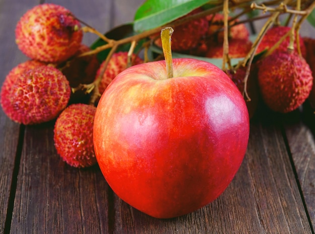 Manzana y lichis en mesa de madera