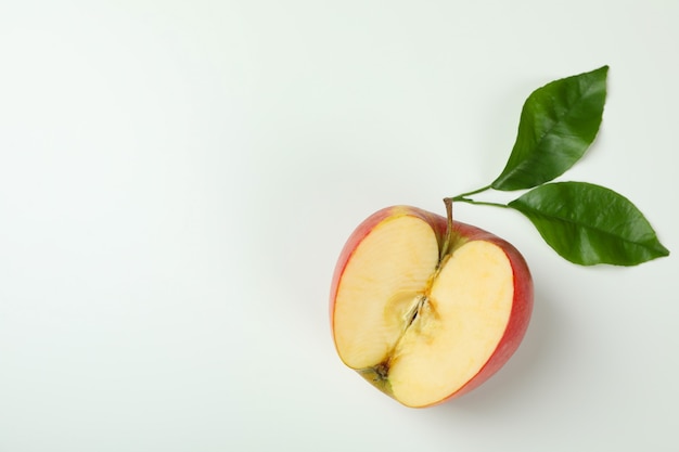 Manzana madura con hojas sobre fondo blanco.