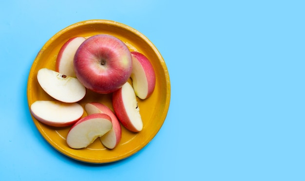 Manzana madura en placa en pared azul.