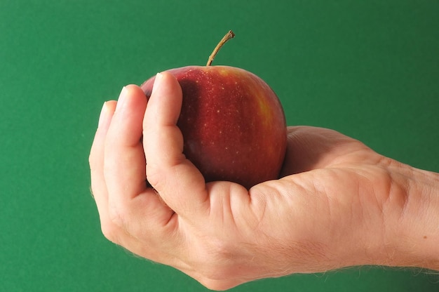 Una manzana en la mano sobre un fondo de color