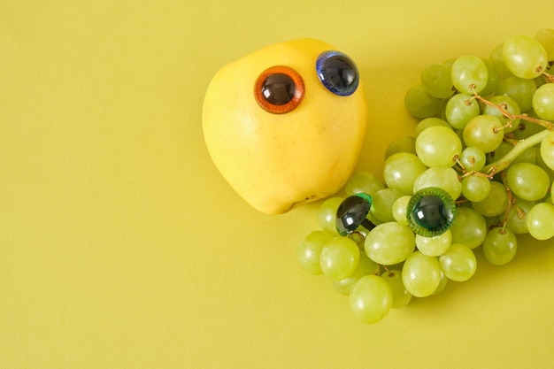 Manzana y racimo de uvas con ojos de marioneta broma concepto fondo verde 1 de abril broma