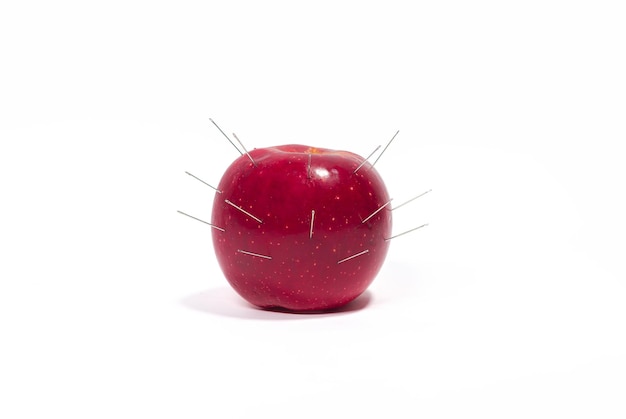 Foto una manzana roja en agujas afiladas psicología ataque de nervios sobreesfuerzo ira sobre un fondo blanco aislado