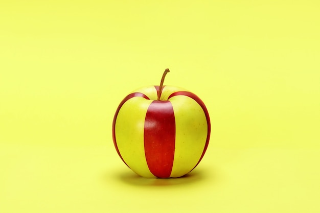 Foto manzana roja y amarilla rayada sobre un fondo amarillo.