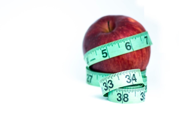 Manzana roja borrosa con cinta métrica aislada en blanco - Concepto de dieta