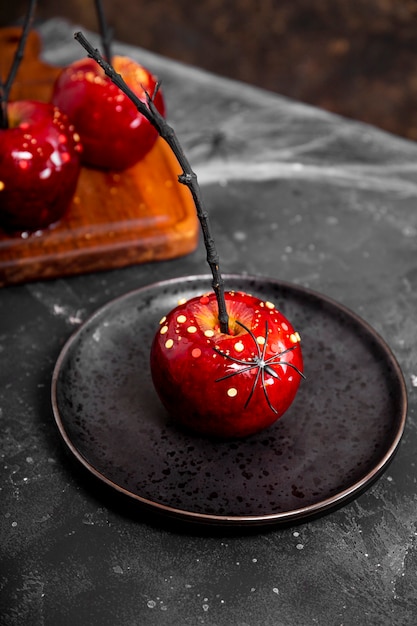 Manzana roja en caramelo con decoración de azúcar en una placa negra un regalo original para una fiesta de halloween