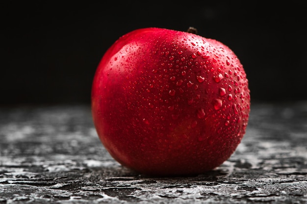 Manzana roja de cerca Manzana roja fresca sobre una textura de fondo negro