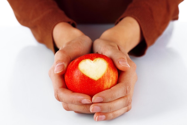 Manzana roja con corazón en primer plano de manos femeninas