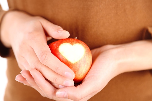 Manzana roja con corazón en primer plano de manos femeninas