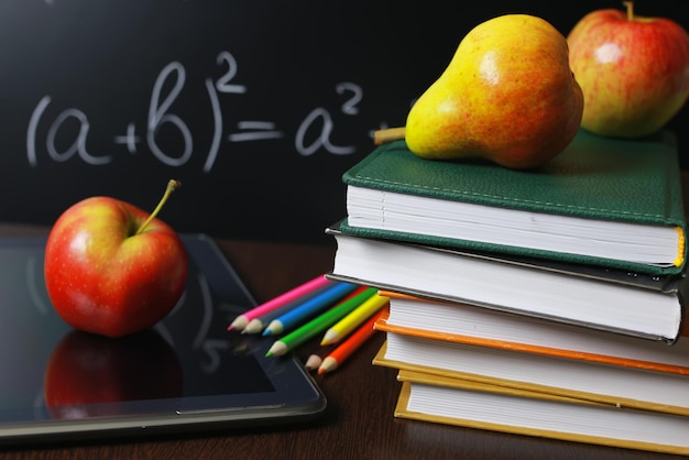 Manzana roja en cuaderno con pila de libros