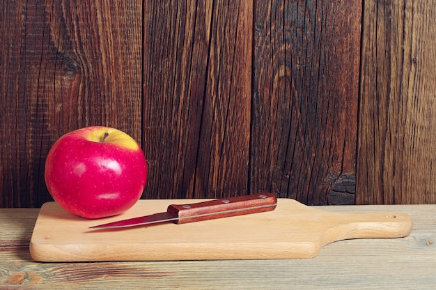 Manzana roja y cuchillo sobre tabla de cortar