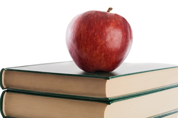 Una manzana roja encima de libros sobre un fondo blanco