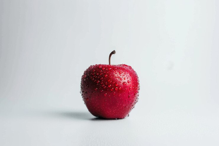 Una manzana roja fresca con gotas de agua en su superficie aislada sobre un fondo blanco limpio que representa la salud y la nutrición