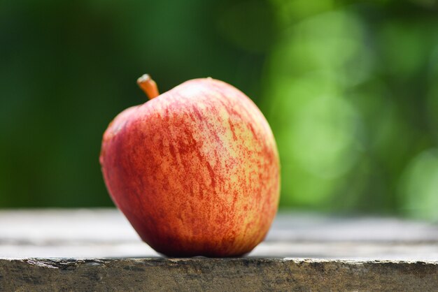 Manzana roja fresca en mesa de madera y naturaleza verde