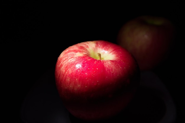 Manzana roja fresca Sobre un fondo negro con gotas de agua, las luces caen con espacio para el texto