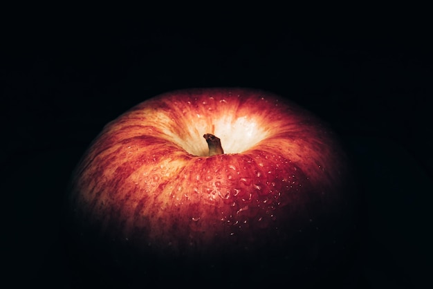 Manzana roja fresca Sobre un fondo negro con gotas de agua, las luces caen con espacio para el texto