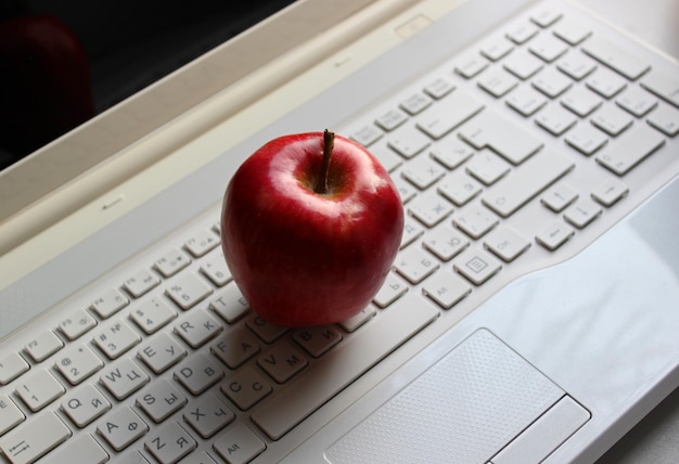 Manzana roja fresca en el teclado de la computadora portátil con caracteres latinos y cirílicos