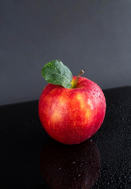 Manzana roja con gotas de agua sobre el fondo oscuro Primer plano