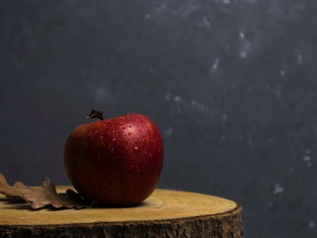 Foto manzana roja en gotas con hojas de roble en un espacio de copia de mesa de madera