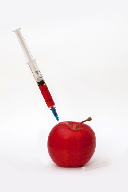 Manzana roja y jeringa médica.