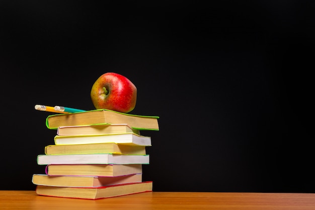 Manzana roja y libros antiguos sobre mesa de madera