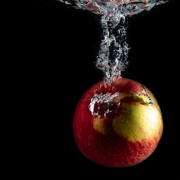 Foto manzana roja madura cae al agua con salpicaduras