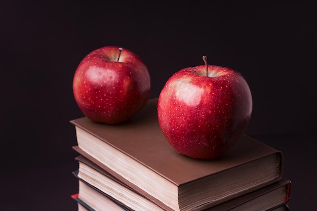 Manzana roja madura encima de libros apilados sobre un fondo negro