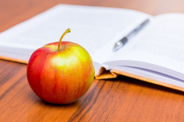 Manzana roja madura jugosa en el fondo de un libro abierto