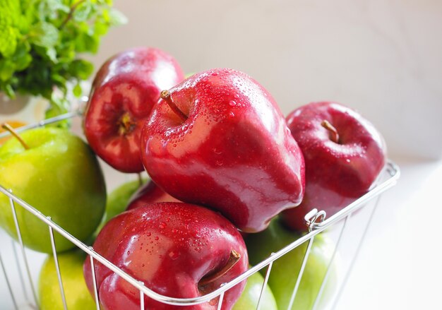 Manzana roja y manzana verde en la cesta en la mesa blanca