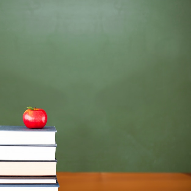 Manzana roja en pila de libros en el aula